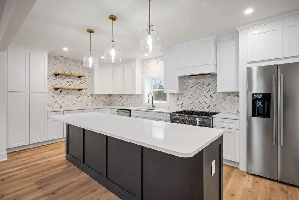 White shaker kitchen with a charcoal island and brass pendants — a completed CMD Property Restoration Group kitchen