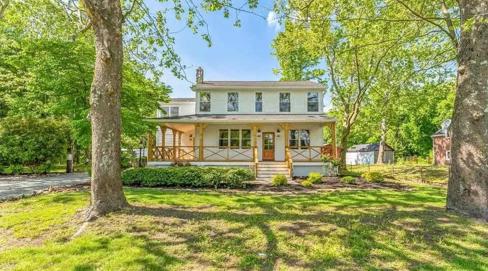 Two-story farmhouse with a wraparound porch after a full renovation for resale — a completed CMD whole-home project