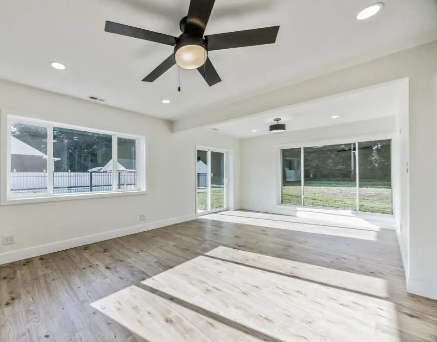 Great room with a ceiling fan, new sliding doors and windows to the yard, and light oak floors — a completed CMD whole-home renovation