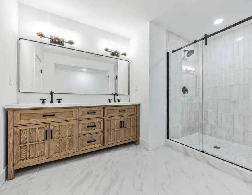 Primary bathroom with a white oak double vanity, black fixtures and a black sliding barn-style glass shower door — a completed CMD whole-home renovation