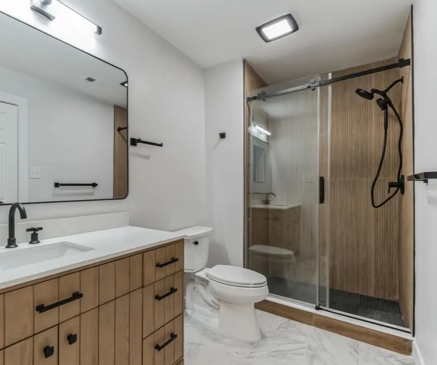Full bathroom with an oak vanity, black fixtures and a sliding glass shower — a completed CMD whole-home renovation