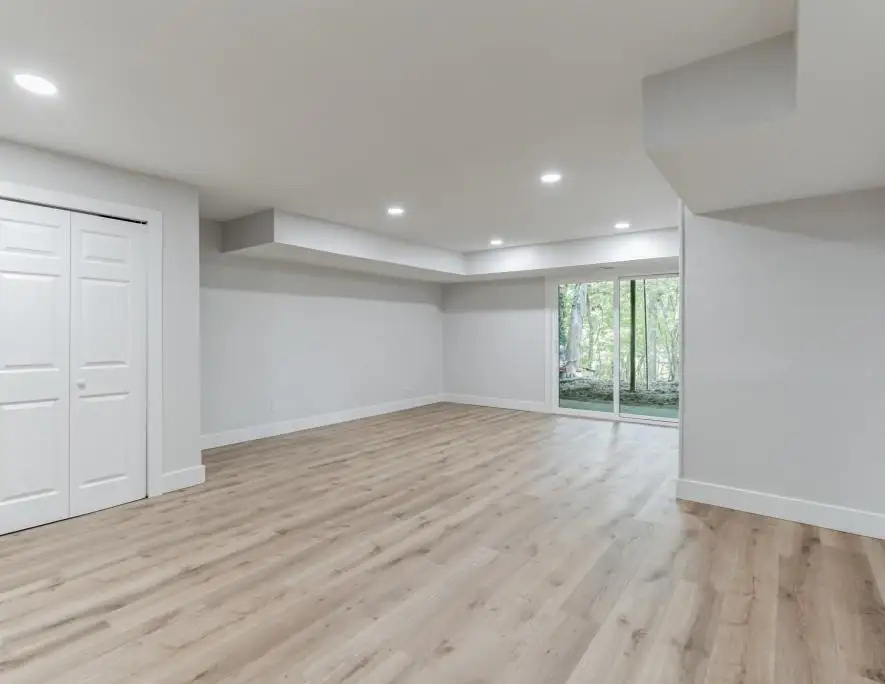 Finished lower level with recessed lighting, plank flooring and a walk-out to the yard — a completed CMD project