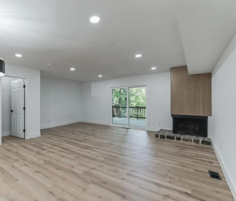 Living room with a wood-surround fireplace, stone hearth and sliding doors to the deck — a completed CMD whole-home renovation